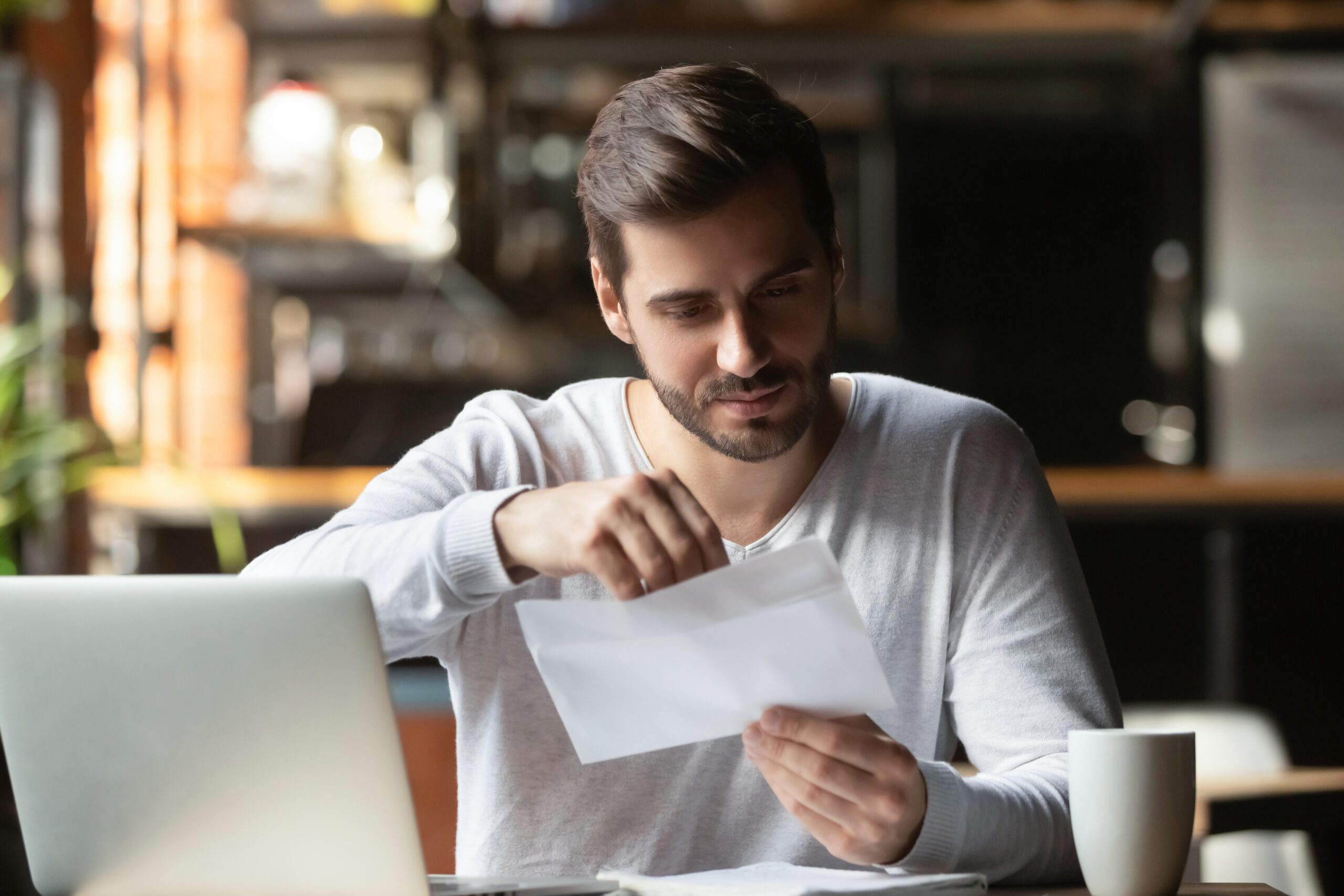 A focused man opens a piece of direct mail for borrowers-without-trigger-leads blog.